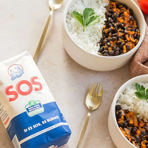 A bowl of white rice with black beans and vegetables, garnished with parsley, next to a package of SOS rice.