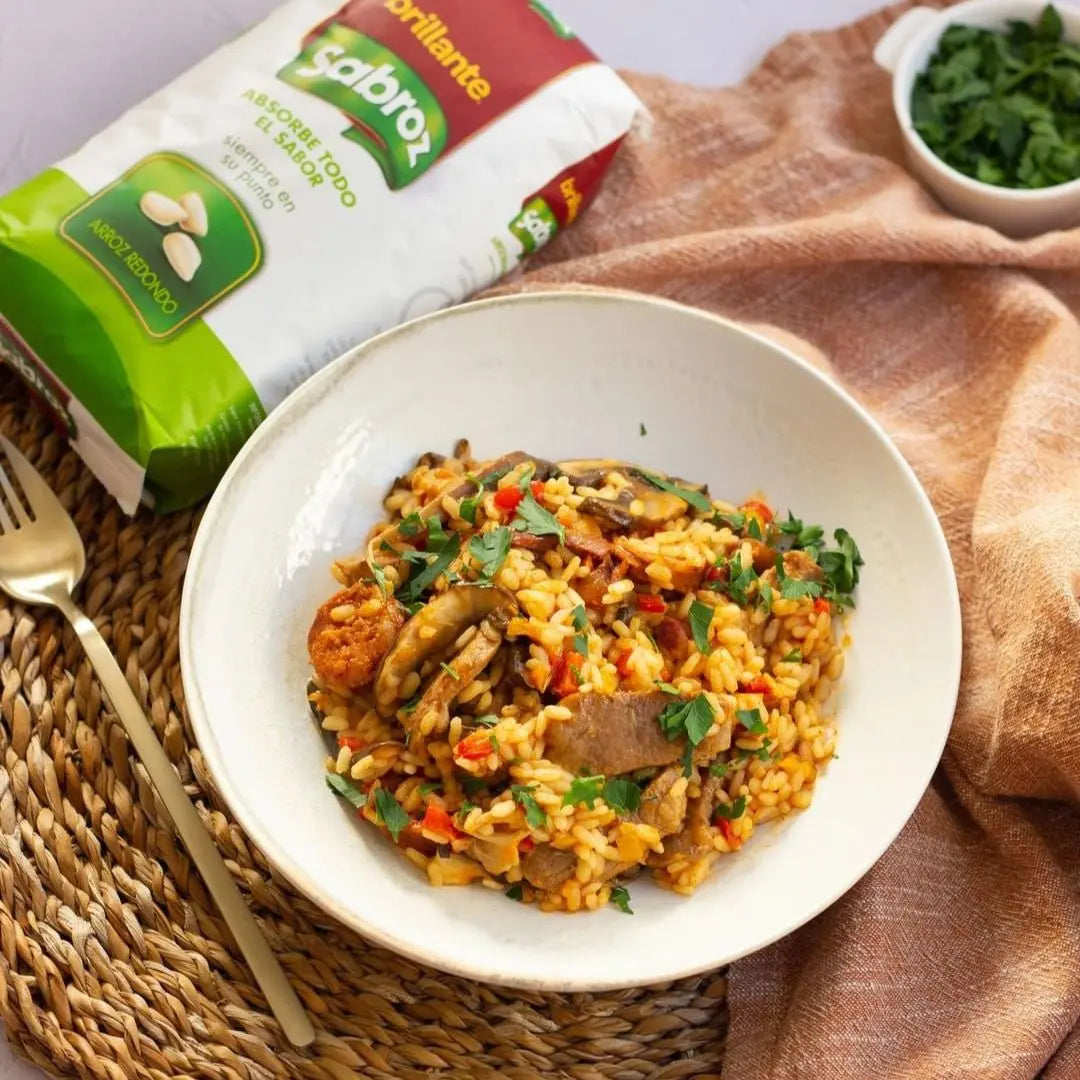 A hearty dish of mushroom and chorizo rice garnished with parsley, with Sabroz rice prominently featured