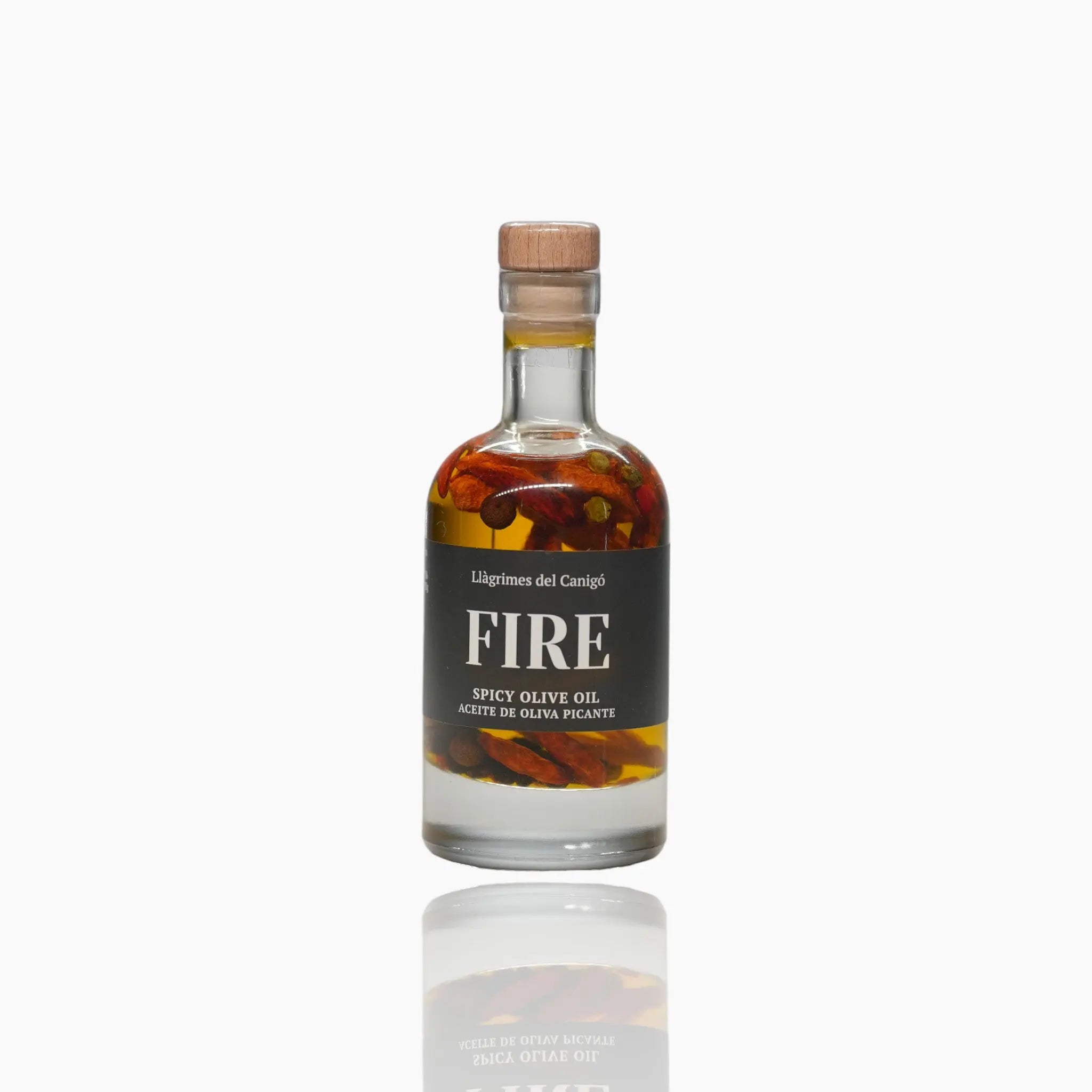 A stylish glass bottle of Llagrimes del Canigó Fire Spicy Olive Oil, showing chili peppers infused inside.